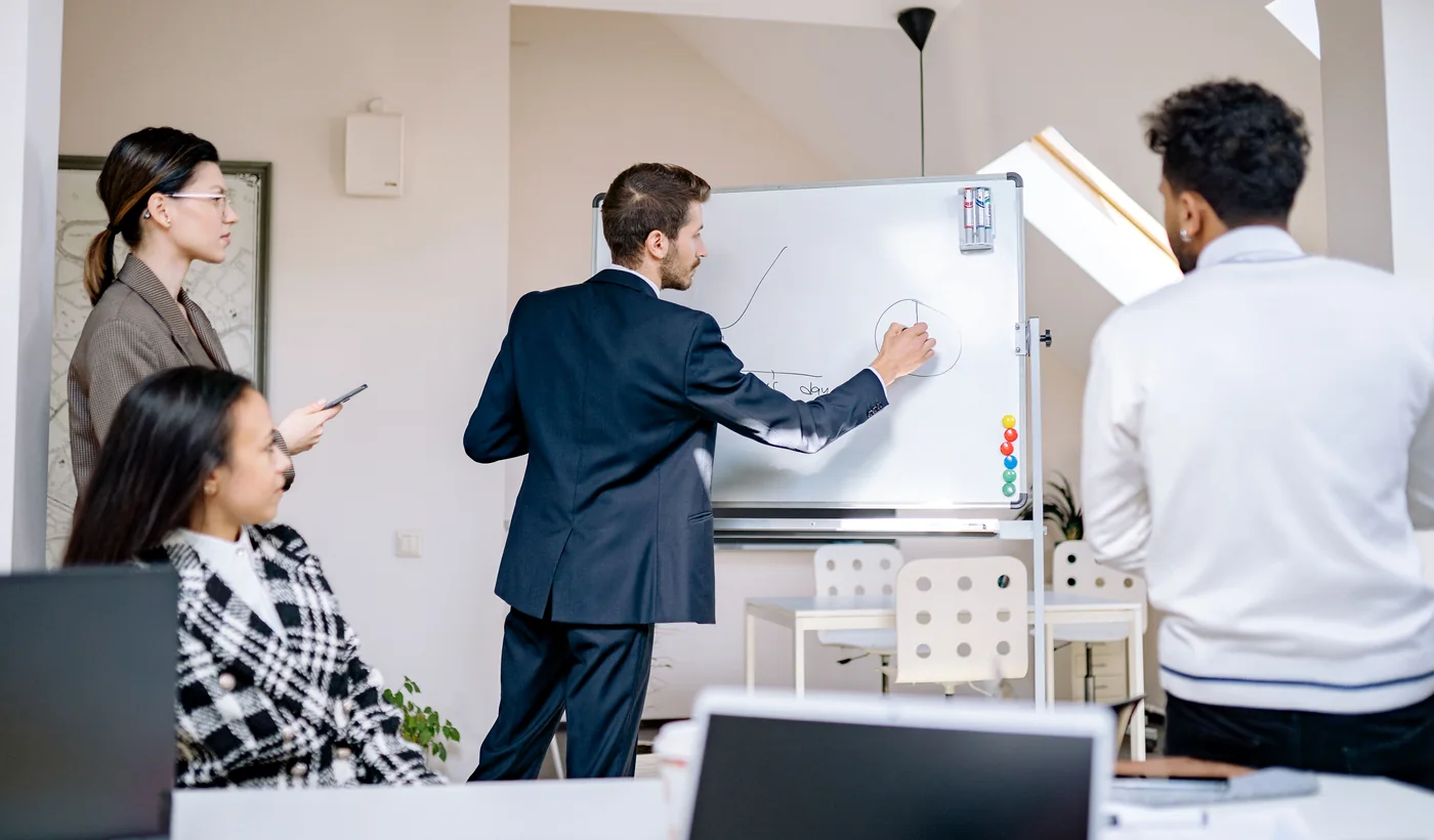Équipe en formation autour d’un tableau blanc dans une entreprise